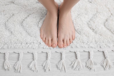 Woman standing on soft white carpet at home, top view