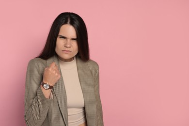 Photo of Aggressive young woman on pink background, space for text