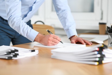 Man working with documents at wooden table in office, closeup