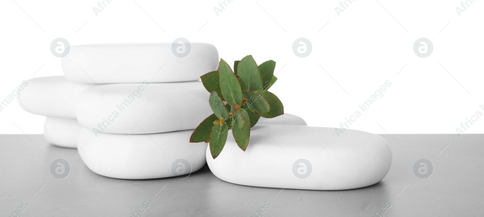 Photo of Spa stones with eucalyptus on table against white background. Space for text