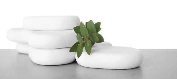 Spa stones with eucalyptus on table against white background. Space for text