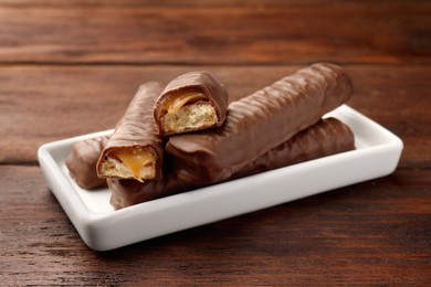 Photo of Sweet tasty chocolate bars with caramel on wooden table
