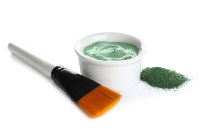 Photo of Freshly made spirulina facial mask in bowl, powder and brush on white background
