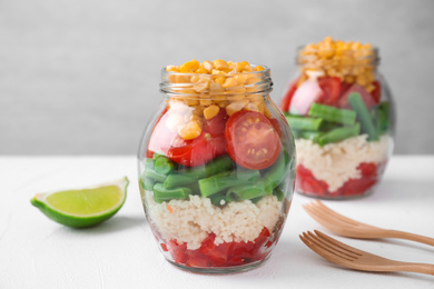 Photo of Healthy salad in glass jars on white table