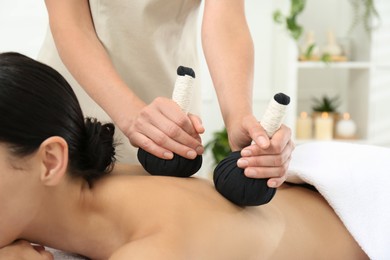 Photo of Young woman receiving herbal bag massage in spa salon, closeup