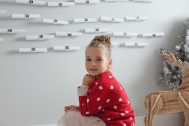 Little girl sitting near New Year advent calendar at home