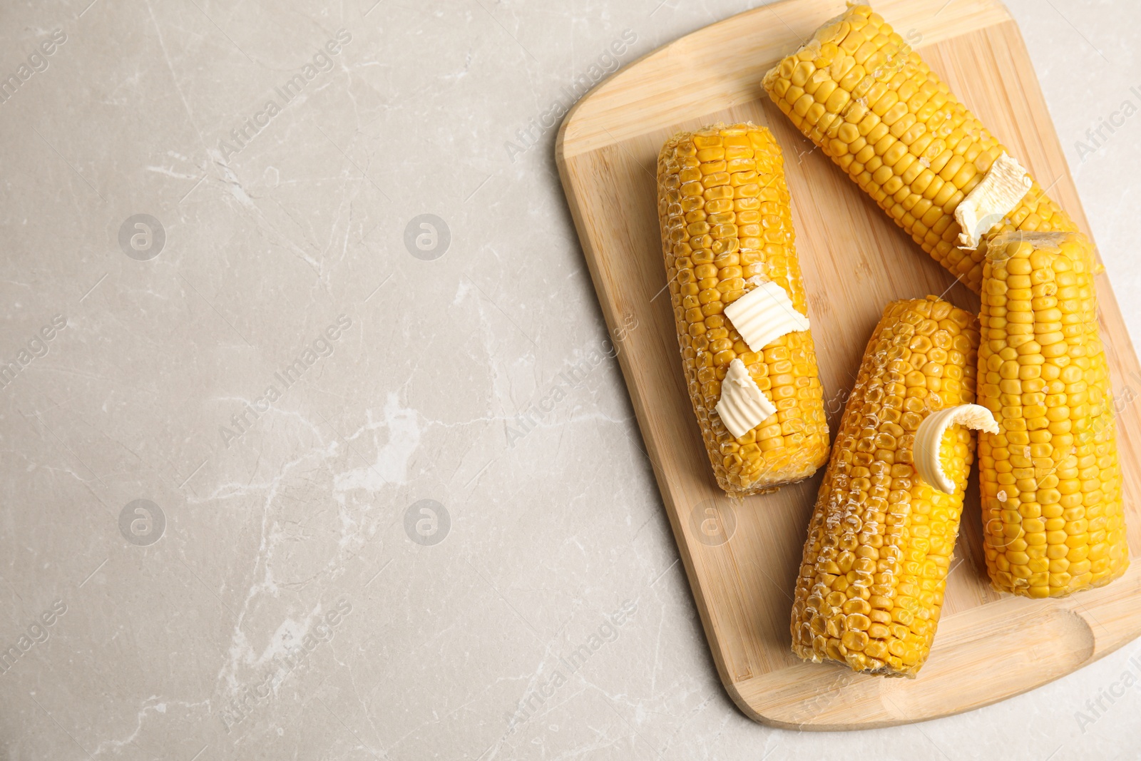 Photo of Delicious boiled corn on light grey marble table, top view. Space for text