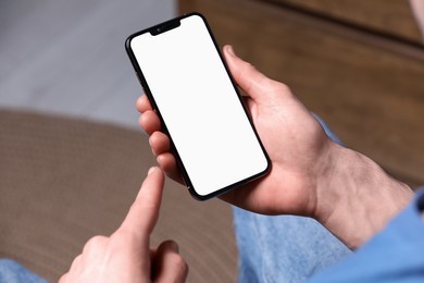 Photo of Man holding smartphone with blank screen indoors, closeup. Mockup for design