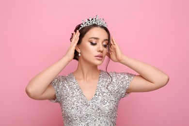 Beautiful young woman wearing luxurious tiara on pink background