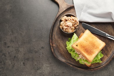 Delicious sandwich with tuna, lettuce leaves and knife on grey table, top view. Space for text