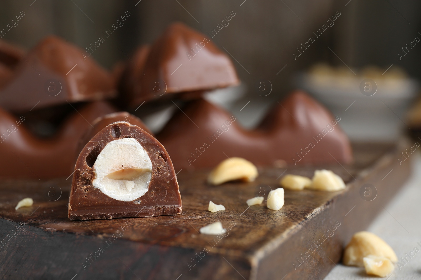 Photo of Tasty chocolate bar with nuts on wooden board, closeup. Space for text