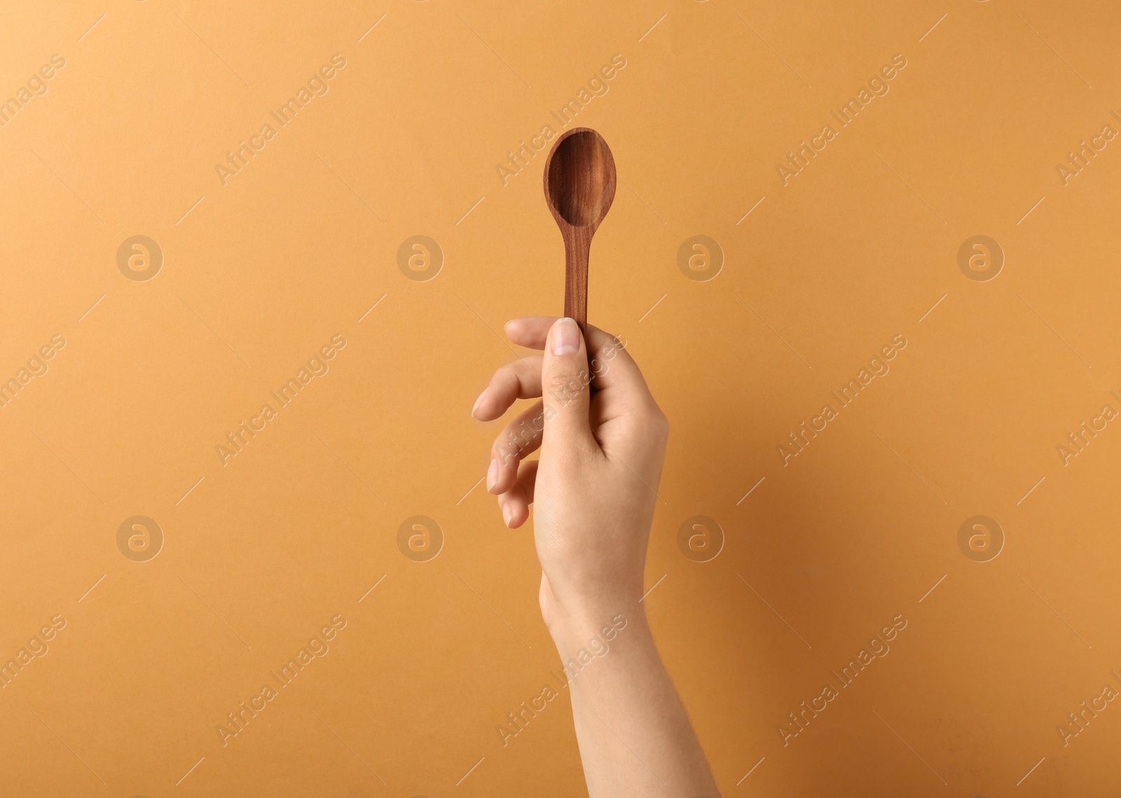 Photo of Woman holding empty wooden spoon on color background, closeup. Space for text