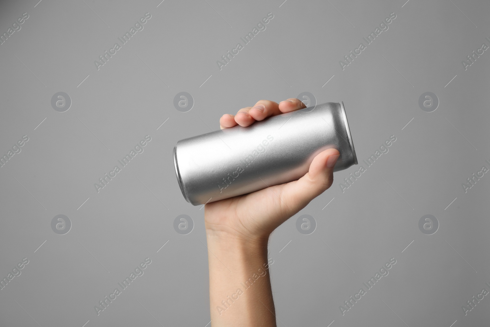 Photo of Woman holding aluminum can with beverage on grey background, closeup. Space for design