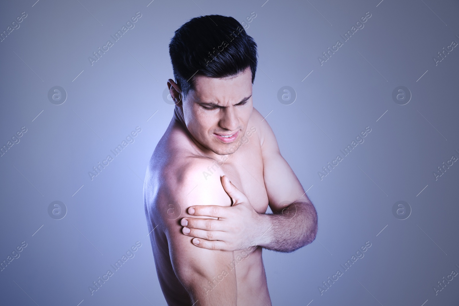 Image of Man suffering from shoulder pain on color background