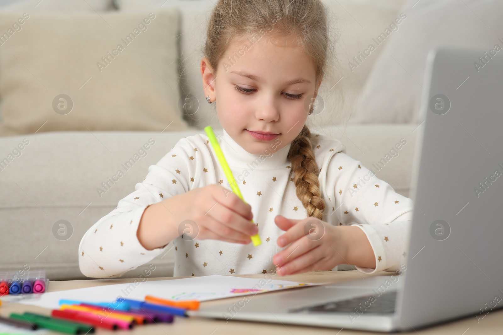 Photo of Little girl drawing with felt-tip pen following online course at home. Time for hobby