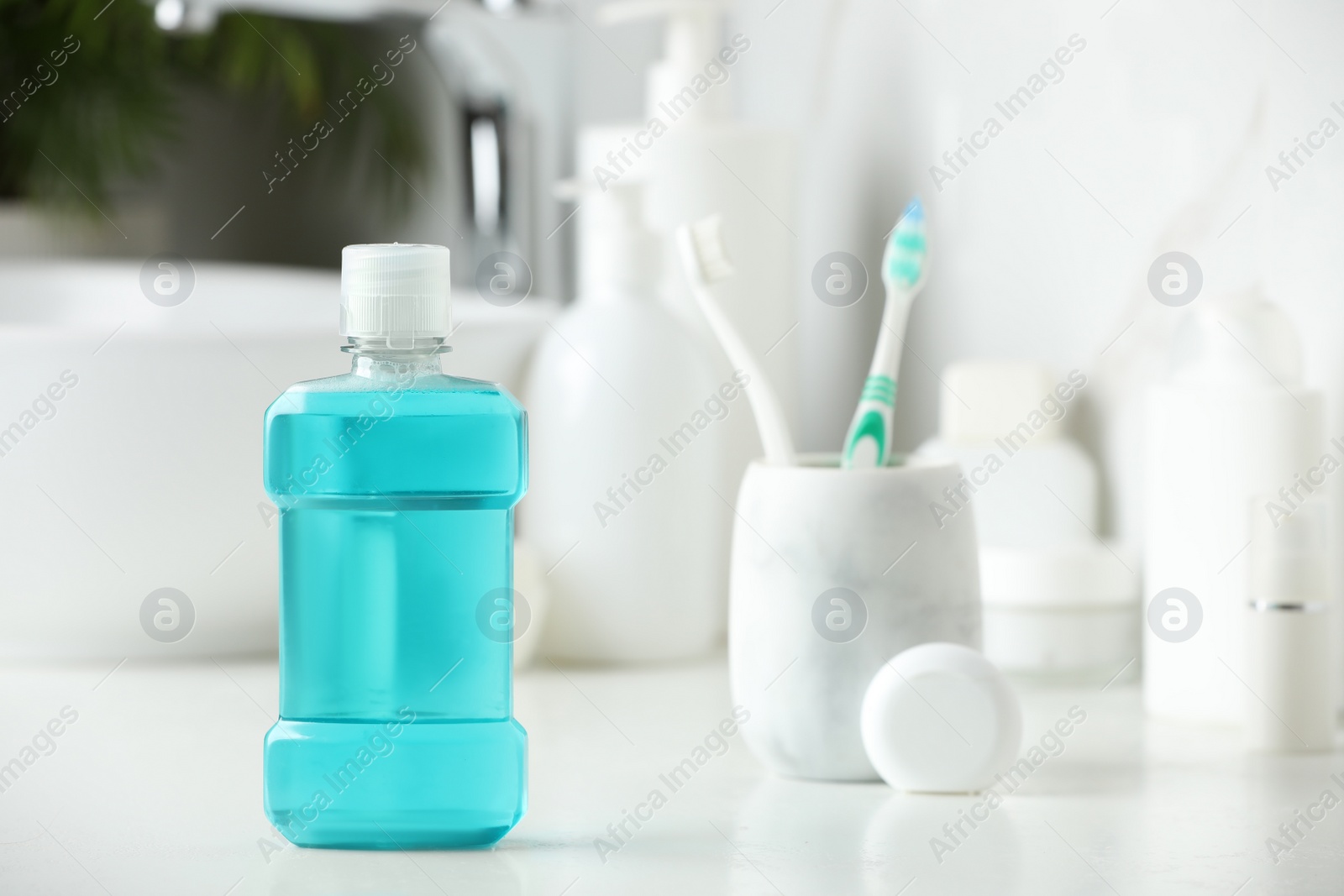 Photo of Mouthwash, toothbrushes and dental floss on white countertop in bathroom. Space for text