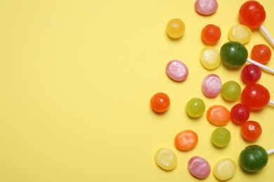 Photo of Many different hard candies on yellow background, flat lay. Space for text