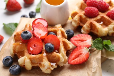 Photo of Delicious Belgian waffles with fresh berries and honey on table, closeup