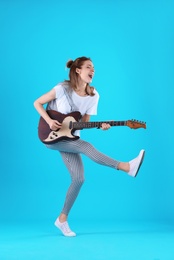 Photo of Young woman playing electric guitar on color background