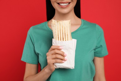Photo of Young woman with delicious shawarma on red background, closeup