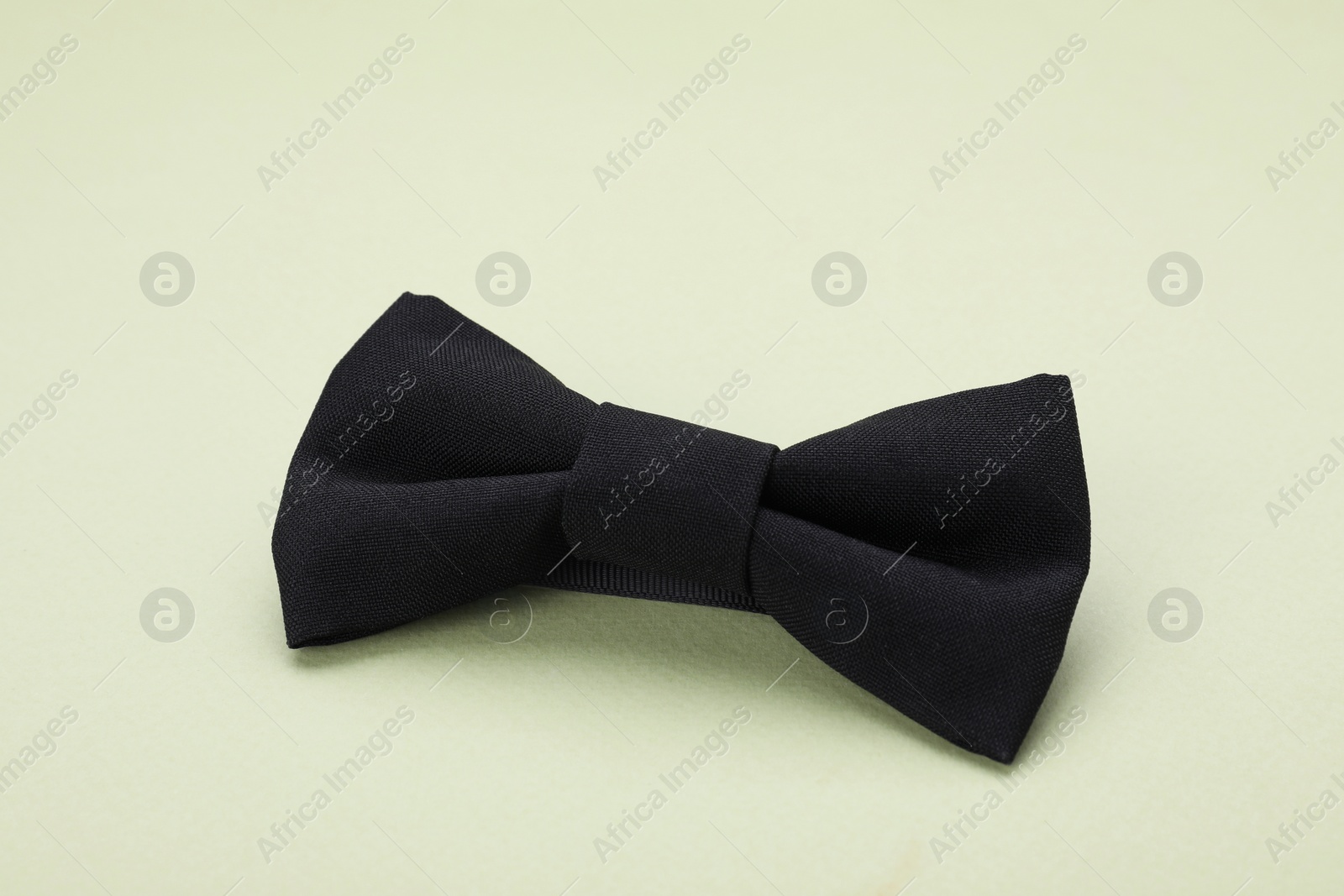 Photo of Stylish black bow tie on pale green background