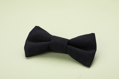Photo of Stylish black bow tie on pale green background