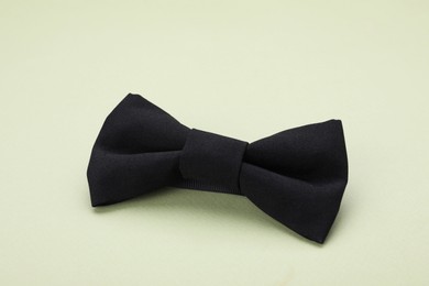 Stylish black bow tie on pale green background