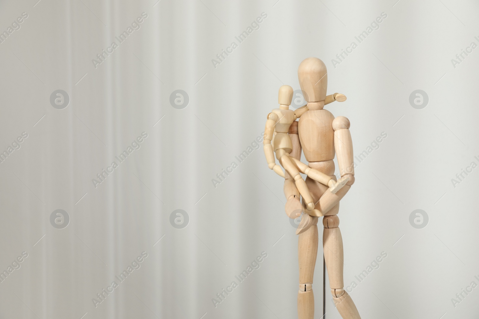 Photo of Wooden mannequins of parent with child on light background, space for text. Family Day