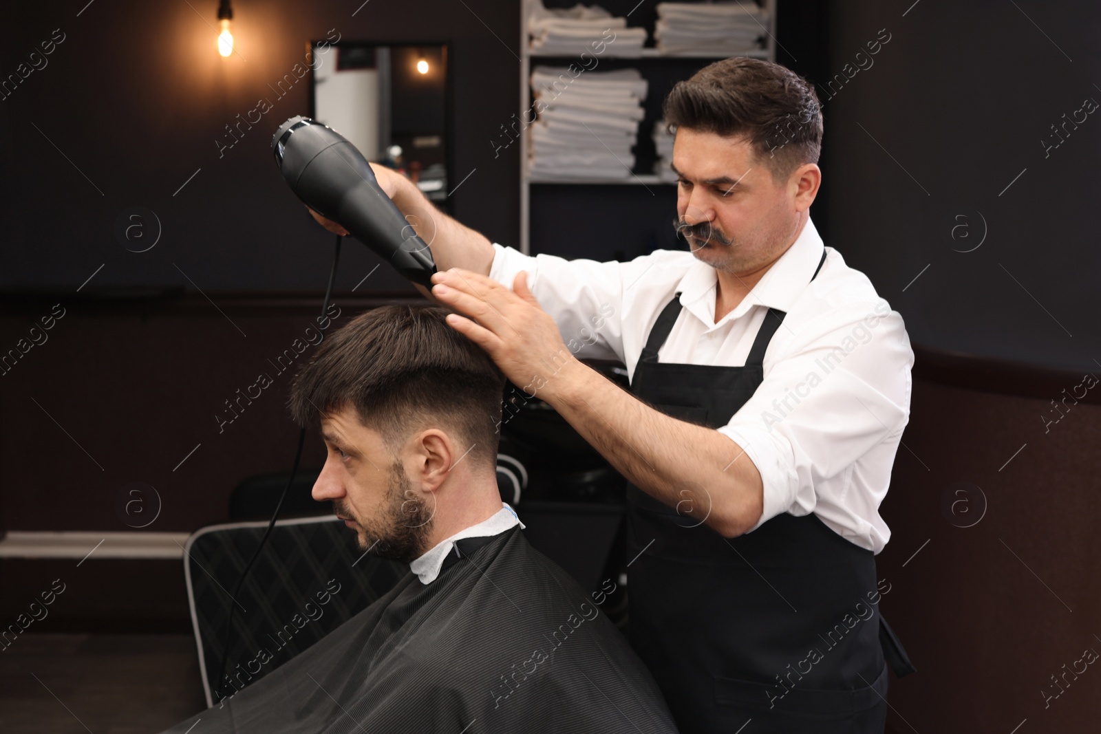 Photo of Professional hairdresser working with client in barbershop