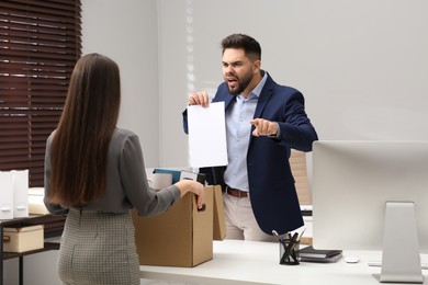 Boss dismissing young woman from work in office