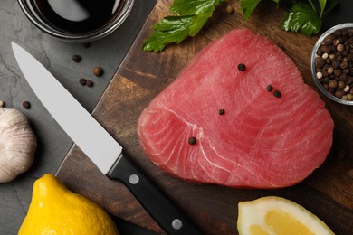 Photo of Raw tuna fillet, spices and knife on wooden board, flat lay
