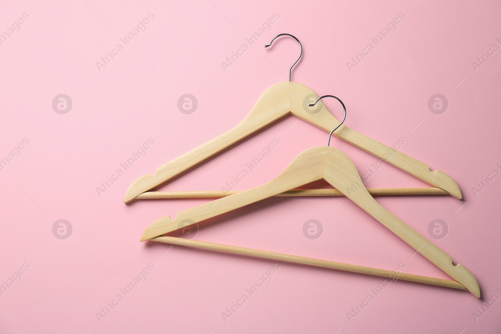 Photo of Wooden hangers on pink background, top view. Space for text