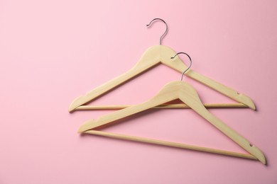 Photo of Wooden hangers on pink background, top view. Space for text