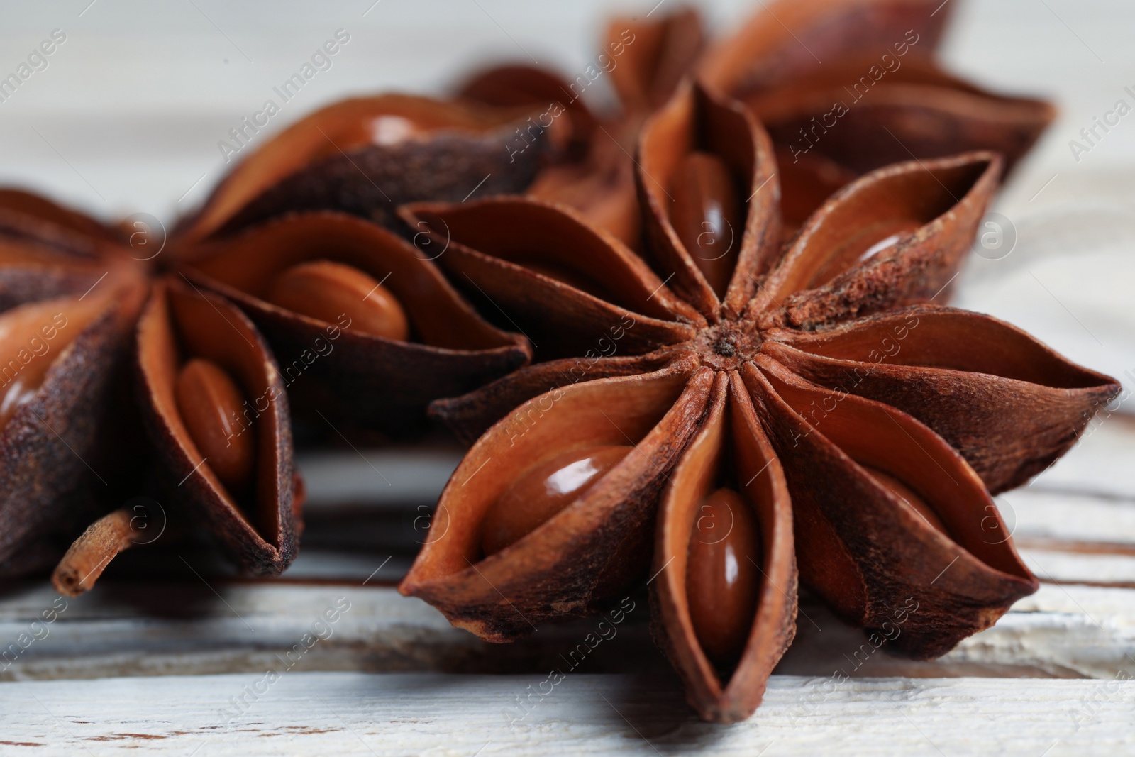 Photo of Aromatic anise stars on white wooden table, closeup