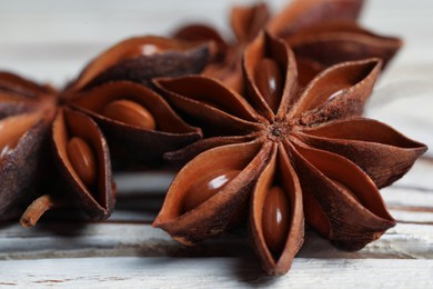 Photo of Aromatic anise stars on white wooden table, closeup