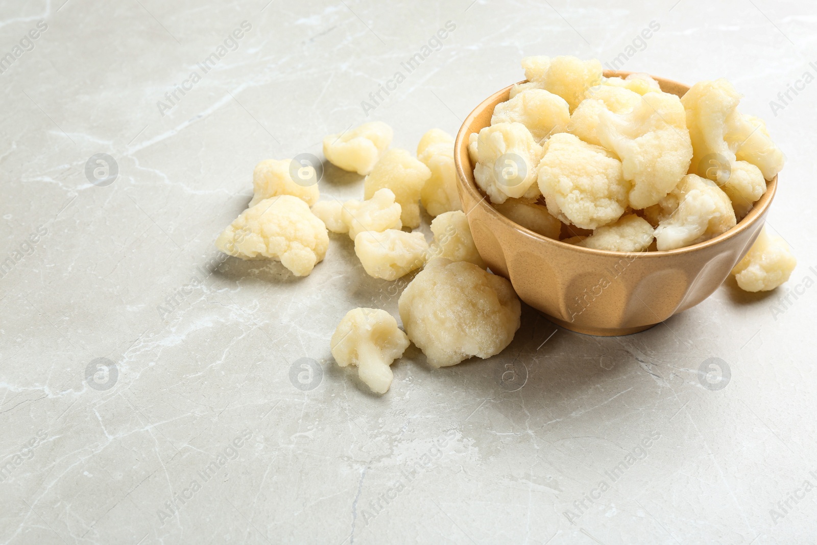 Photo of Frozen cauliflower florets on light grey marble table. Vegetable preservation