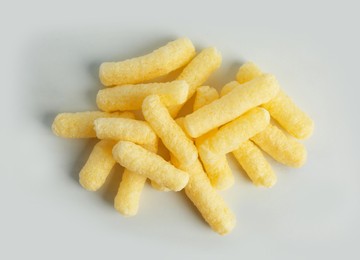 Photo of Pile of delicious crispy corn sticks on white background, flat lay
