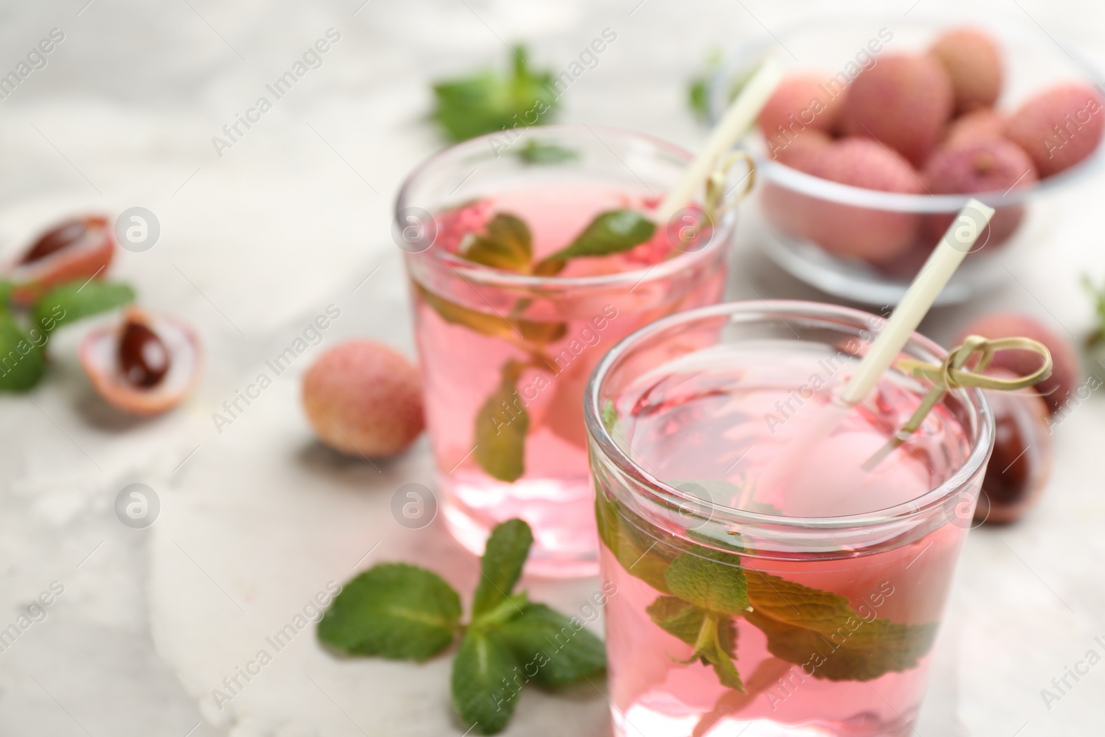 Photo of Lychee cocktail with mint and fresh fruits on grey marble table, closeup