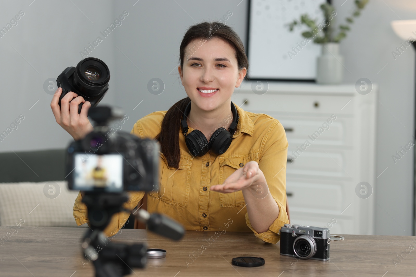 Photo of Smiling technology blogger recording video review about cameras at home