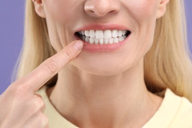 Photo of Woman showing her clean teeth on violet background, closeup view