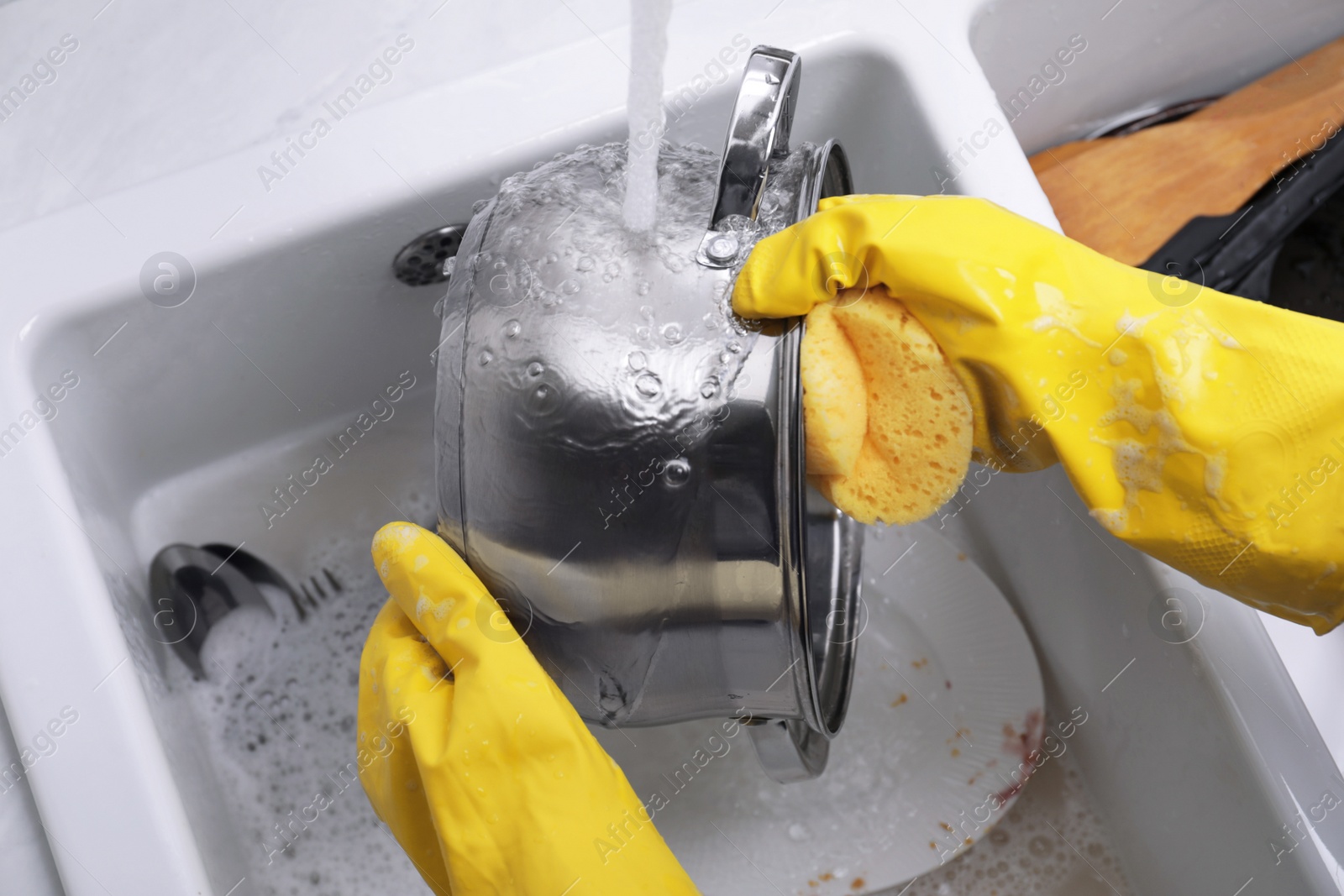 Photo of Woman washing dirty dishes in kitchen sink, closeup