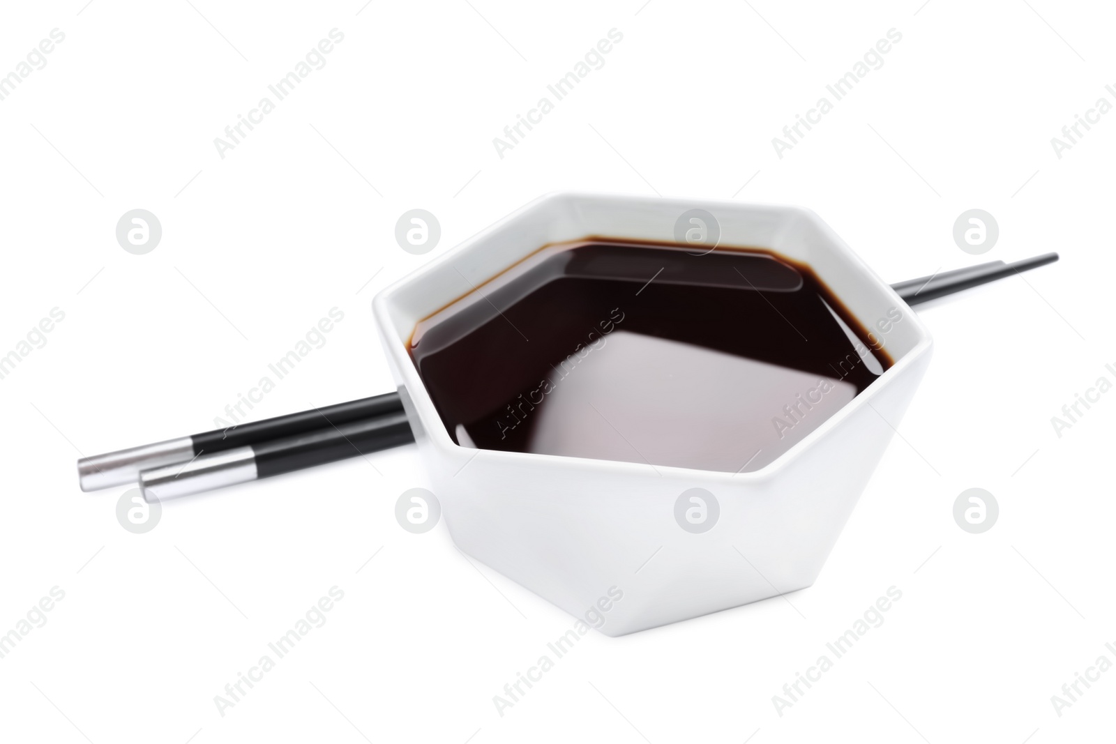 Photo of Bowl of soy sauce with chopsticks on white background