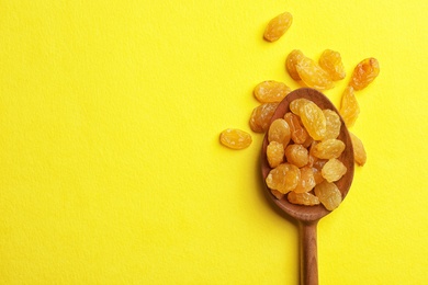 Photo of Spoon with raisins and space for text on color background, top view. Dried fruit as healthy snack