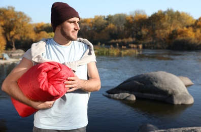 Photo of Male camper with sleeping bag near beautiful lake. Space for text