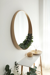 Photo of Round mirror with wooden frame in light room