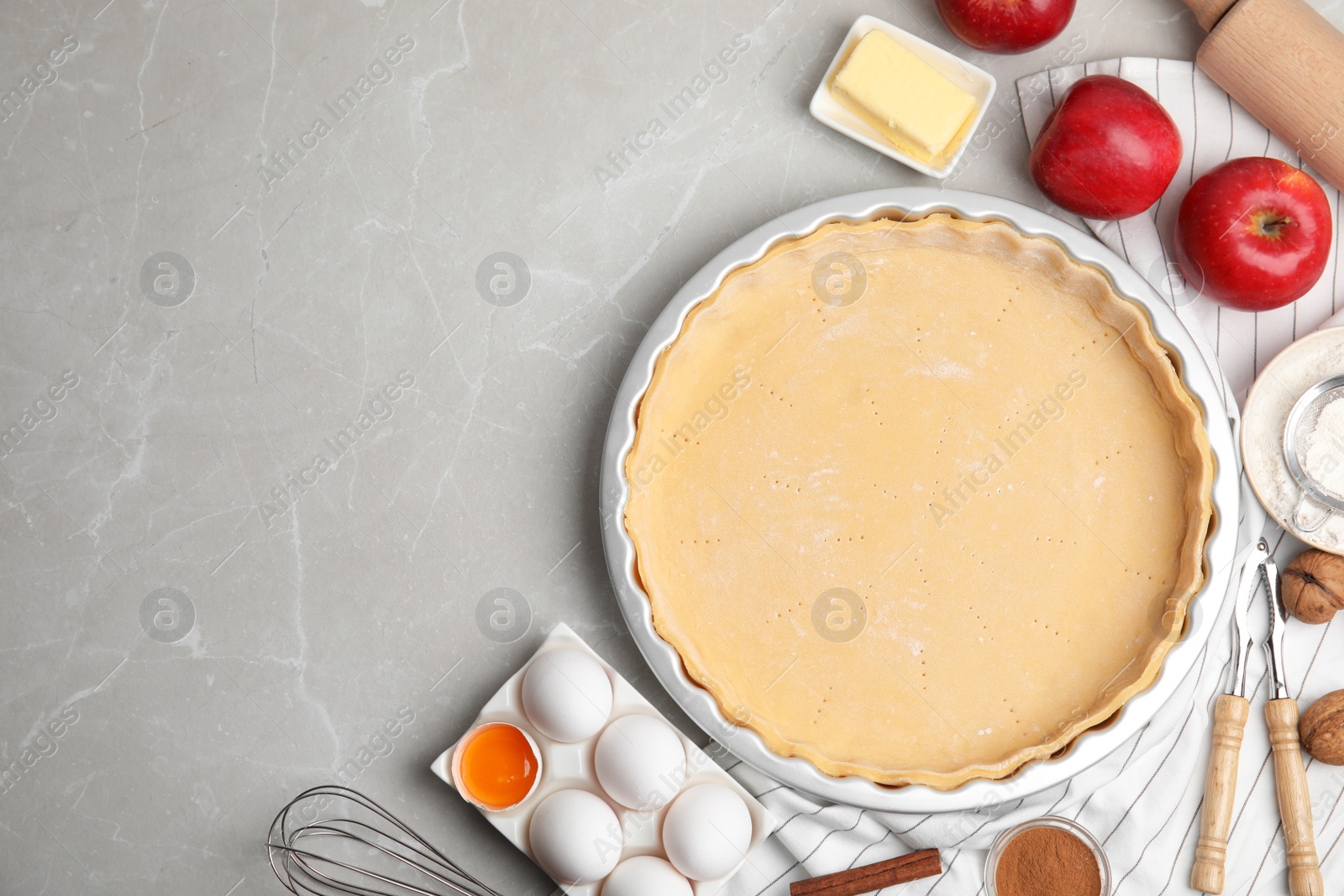 Photo of Raw dough and traditional English apple pie ingredients on light grey marble table, flat lay. Space for text