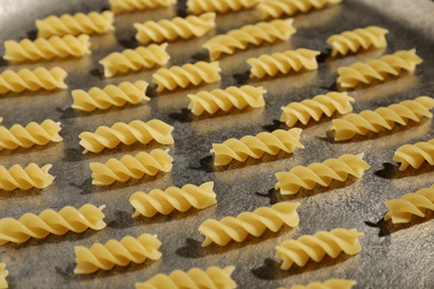 Photo of Uncooked fusilli pasta on grey table, closeup