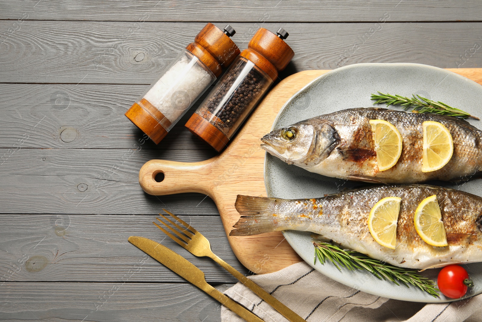 Photo of Delicious baked fish served on grey wooden table, top view. Space for text