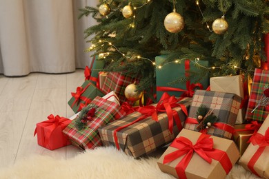 Many gift boxes under beautiful Christmas tree in room
