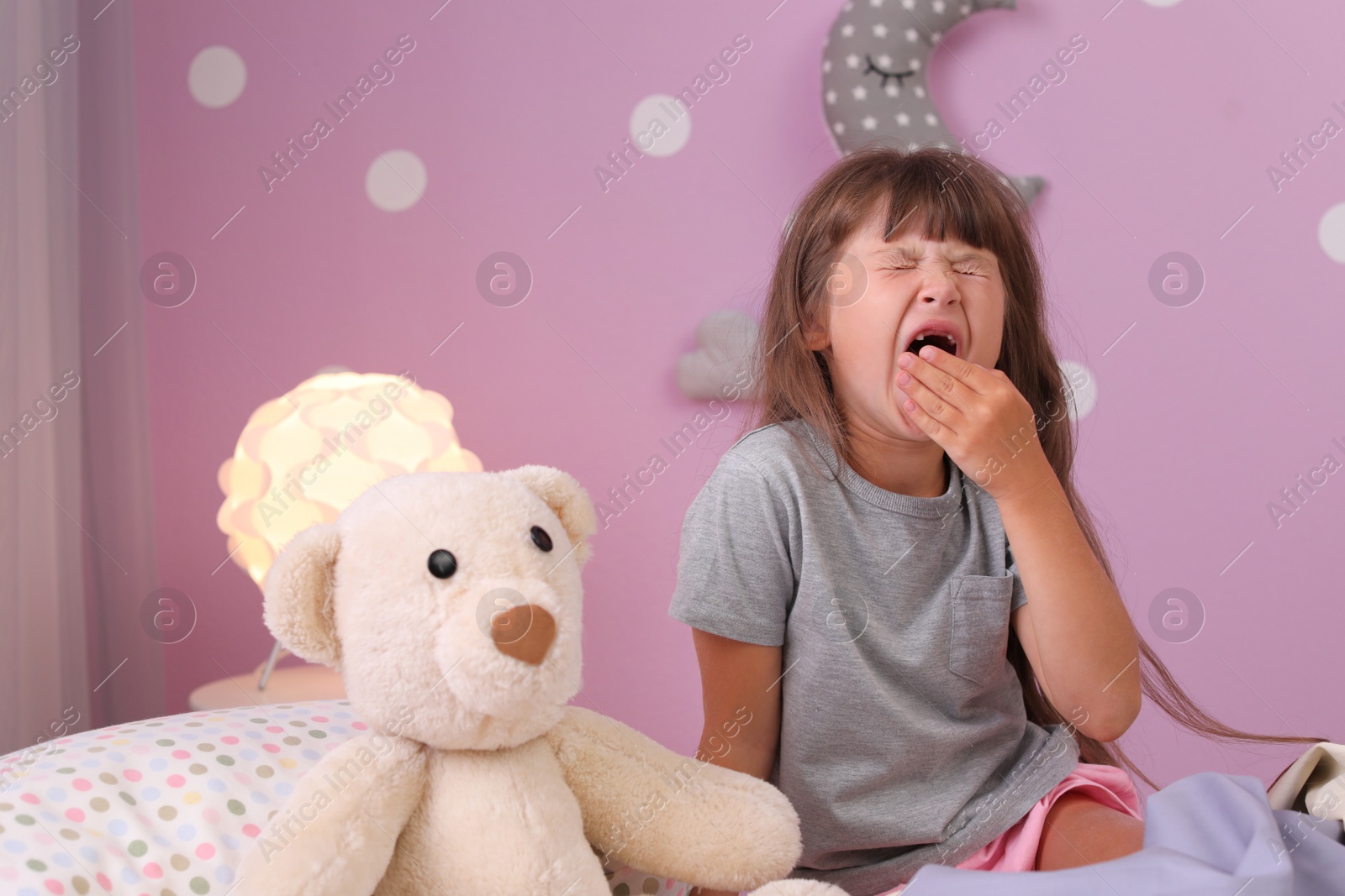 Photo of Little girl yawning on bed at home. Time to sleep